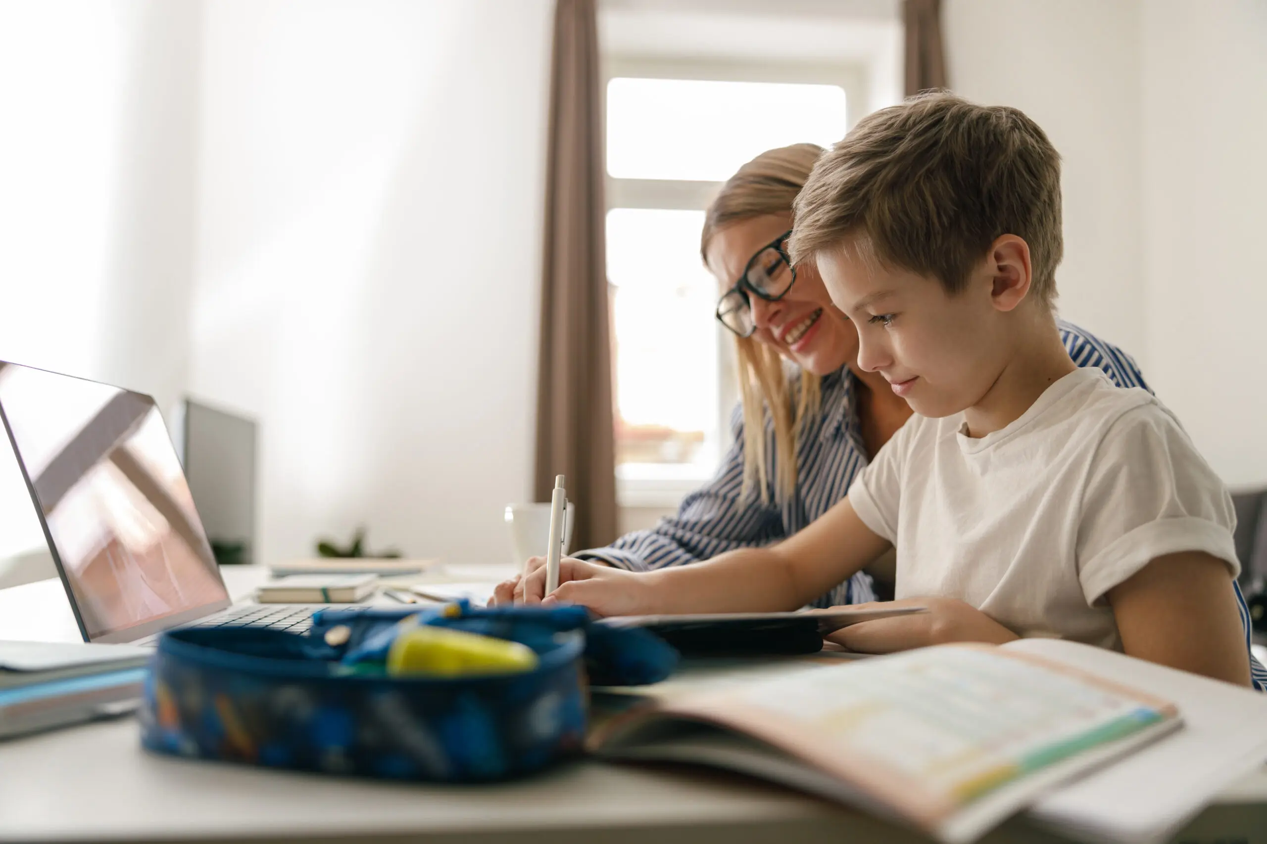Happy mom and son doing homework and studying with laptop together. High quality photo